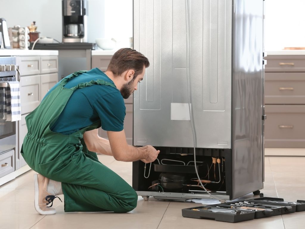 Kỹ thuật viên kiểm tra dàn ngưng và block phía sau tủ lạnh
