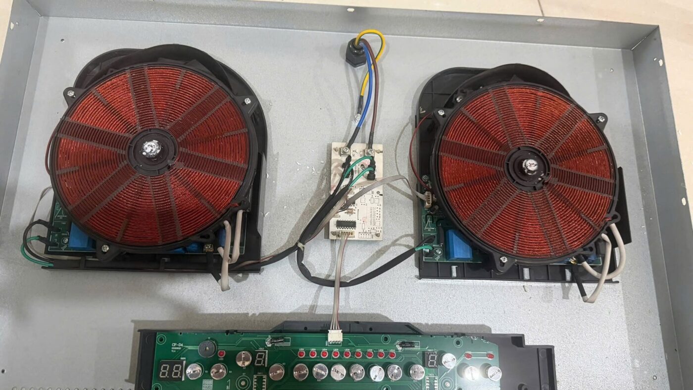 Board điều khiển và hai cuộn dây từ bên trong bếp từ đôi