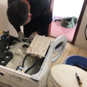 Thợ đeo găng tay mở nắp trên khi sửa máy giặt quận 1 trong nhà tắm