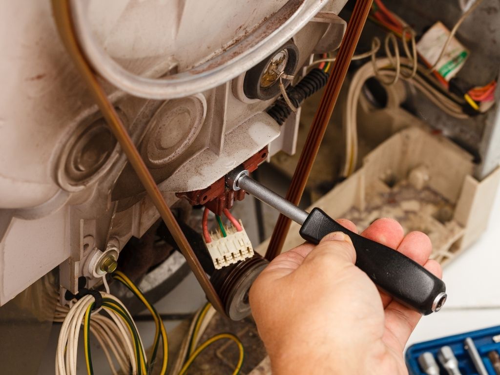 Thợ siết đầu nối dây điện ở cụm motor, ngay cạnh dây curoa của máy giặt đã tháo vỏ