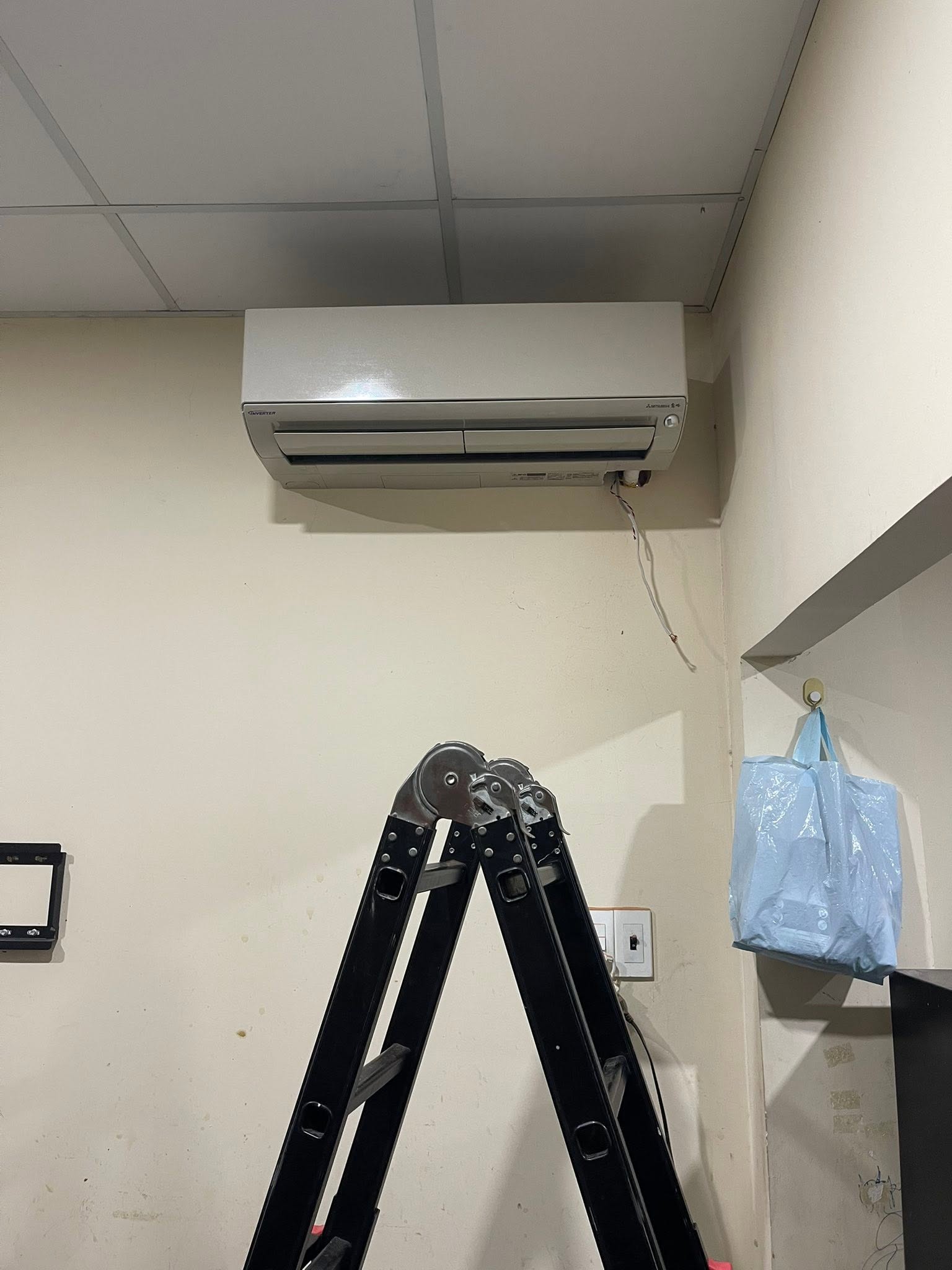 Máy lạnh treo tường Mitsubishi inverter trong phòng, thang gấp đặt sẵn bên dưới cho buổi vệ sinh máy lạnh quận 3