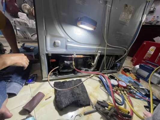 Thợ gắn đồng hồ đo áp suất gas vào block dưới gầm khi sửa tủ lạnh quận 6