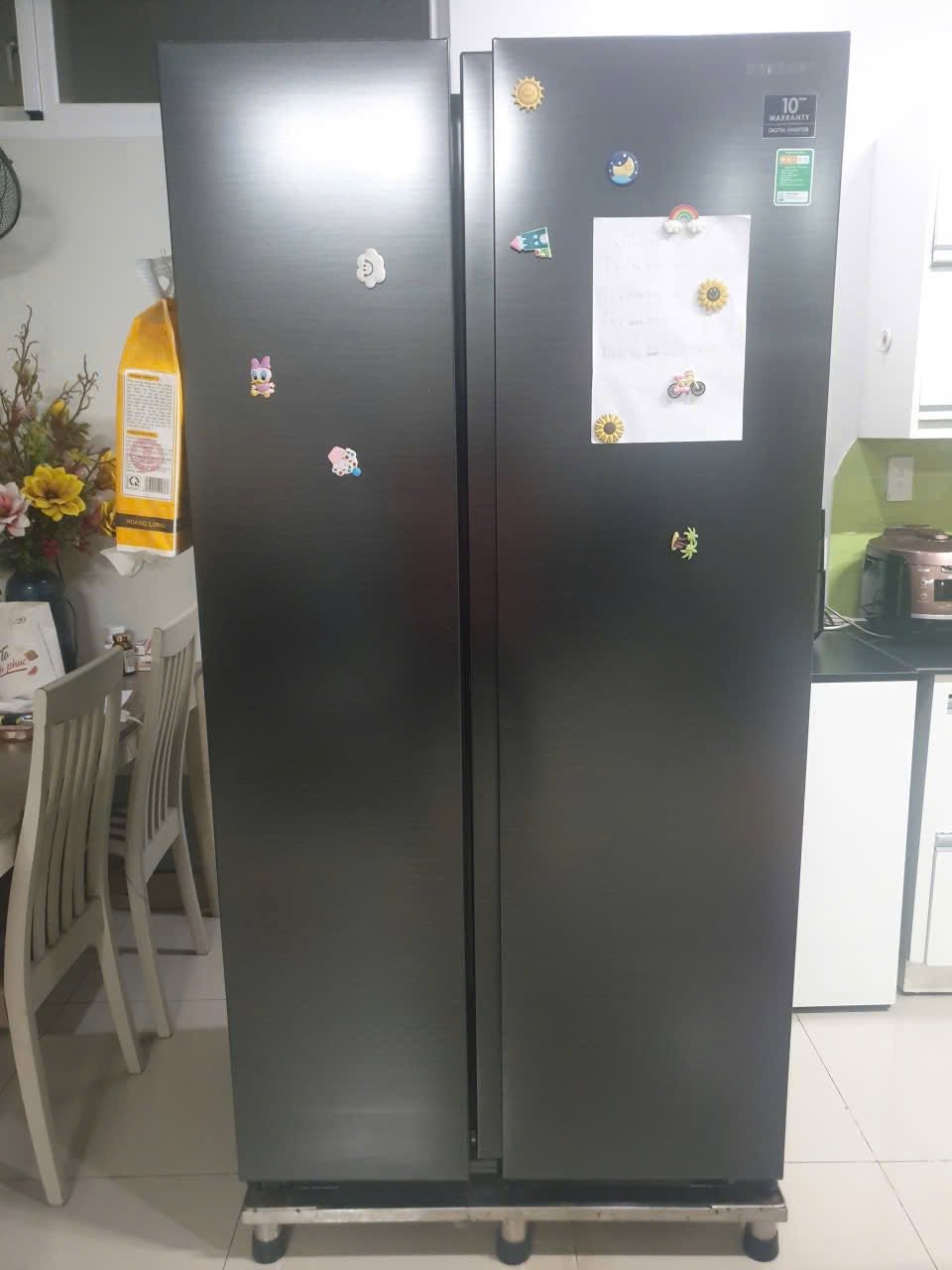 Tủ lạnh side-by-side màu đen kê trên chân đế inox có bánh xe trong bếp