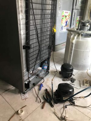 Lưng tủ lạnh lộ dàn nóng, block cũ tháo ra đặt cạnh dụng cụ khi sửa tủ lạnh bình tân