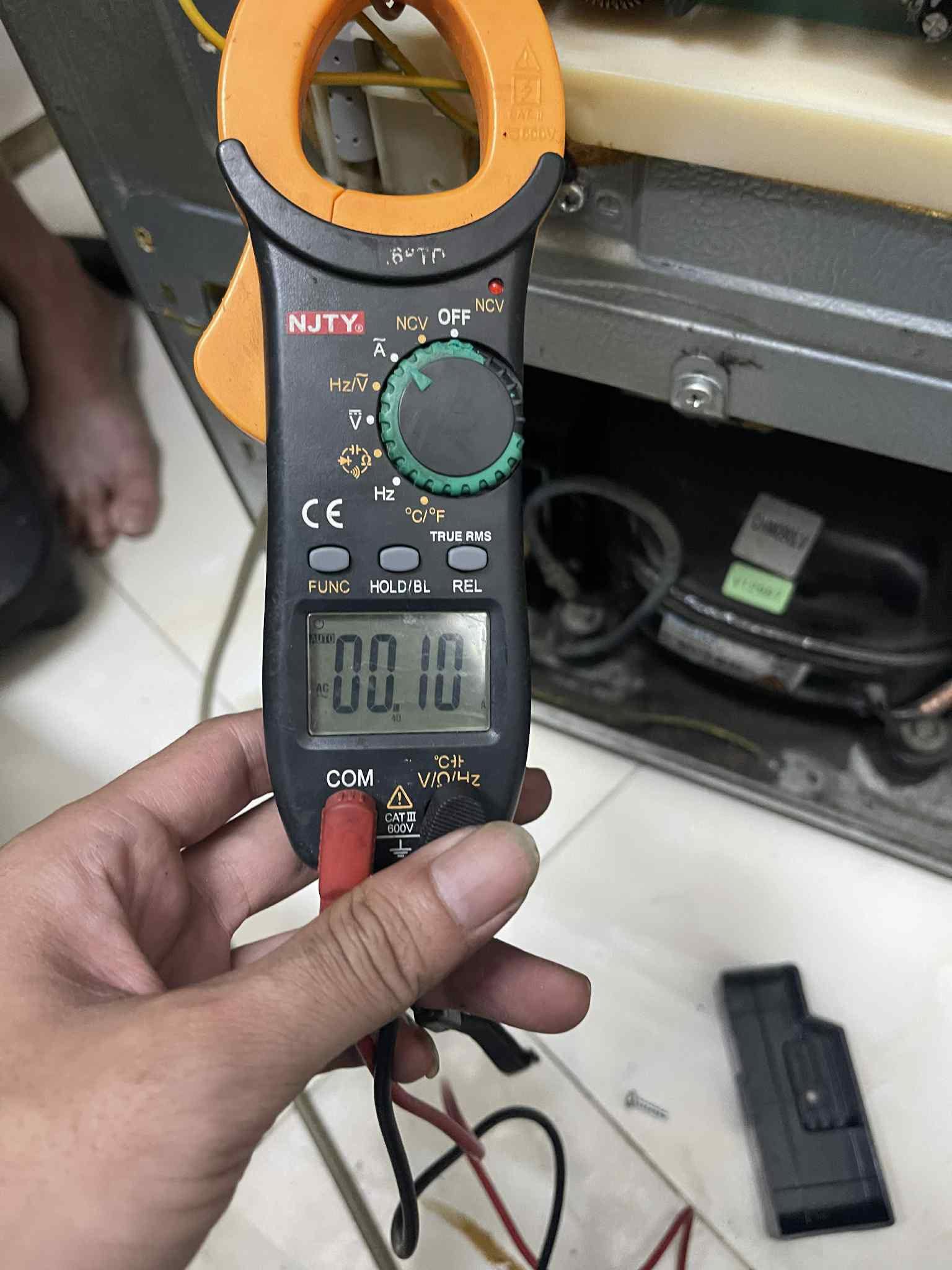 Thợ cầm ampe kìm đo dòng điện cạnh block khi sửa tủ lạnh Thủ Đức tại nhà