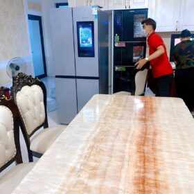 Thợ đeo khẩu trang kiểm tra tủ lạnh side-by-side trong phòng ăn khi sửa tủ lạnh tân bình