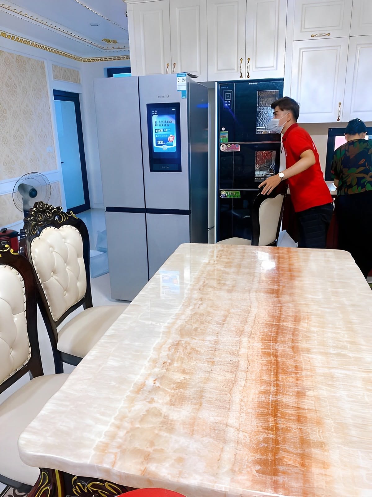 Thợ đeo khẩu trang kiểm tra tủ lạnh side-by-side trong phòng ăn khi sửa tủ lạnh tân bình