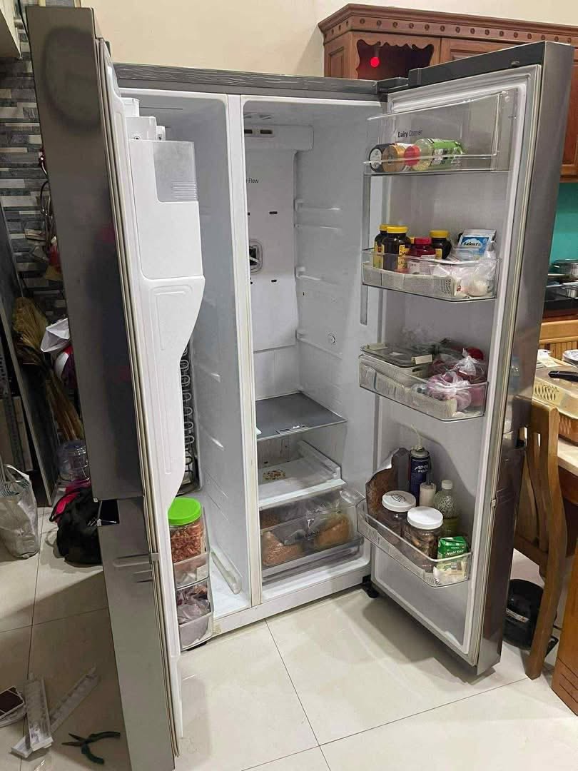 Tủ lạnh side-by-side vỏ bạc mở hai cánh, kệ cửa xếp chai lọ và hộp đồ ăn