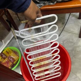 Thợ sửa tủ lạnh Bình Thạnh cầm dàn lạnh tháo rời, ngâm làm sạch trong chậu nước