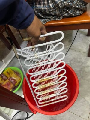 Thợ sửa tủ lạnh Bình Thạnh cầm dàn lạnh tháo rời, ngâm làm sạch trong chậu nước