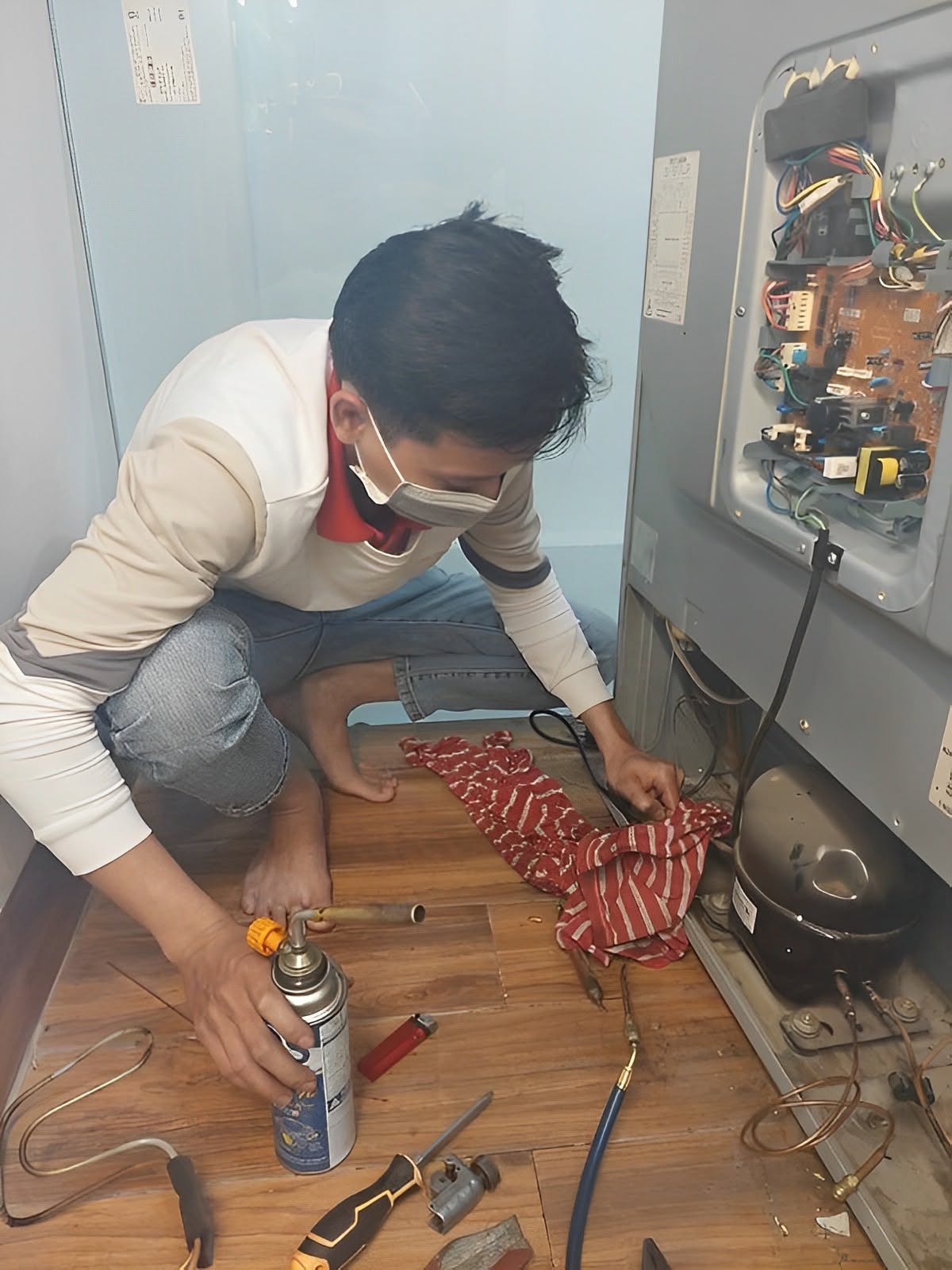 Thợ hàn ống đồng cạnh máy nén trước khi nạp gas